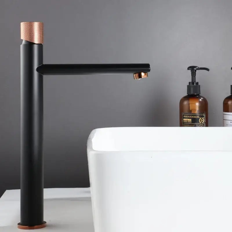 Modern brushed gold brass basin faucet with black matte finish and rose gold accents on handle spout and base