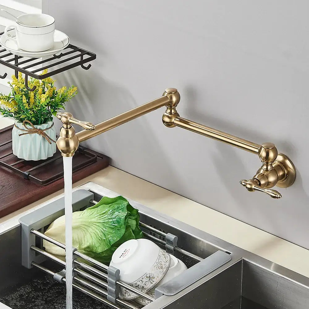 Modern brushed gold pot filler faucet with brass extendable folding spout and ornate spherical handles for kitchen use