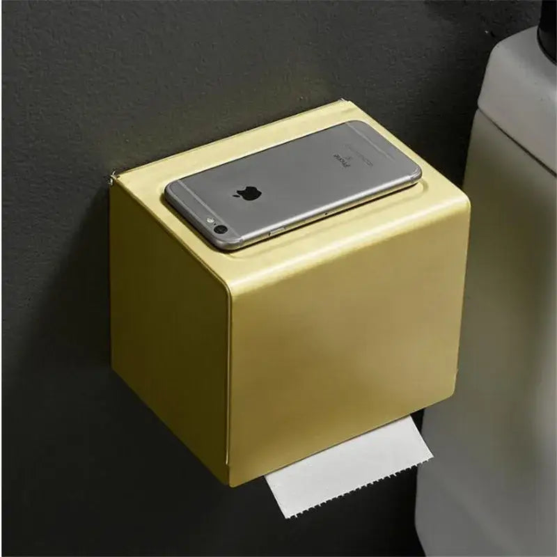 Modern brushed gold toilet paper holder with metallic finish and silver iphone on a gold rectangular paper holder box
