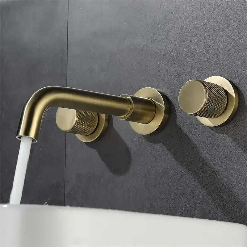Modern brushed gold wall mount faucet with textured circular knobs and curved spout for bathroom fixtures