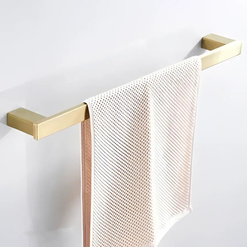 Modern brushed matt gold decorbites bath set towel rack in gold tone holding a light pink mesh towel for bathroom use