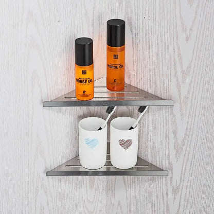 Stainless steel triangular wall shelf with two tiers in a modern brushed nickel bathroom hardware set with glass accents