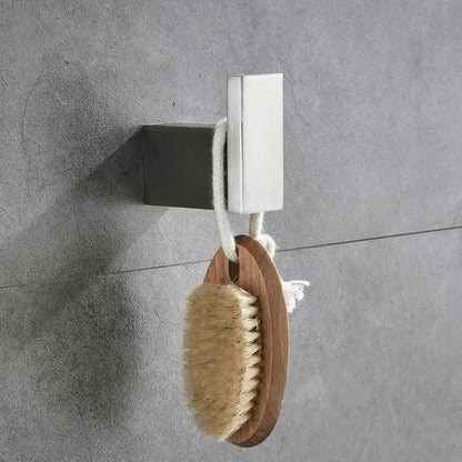 A natural wood handled bath brush with beige bristles hanging on a modern brushed nickel bathroom hardware set hook