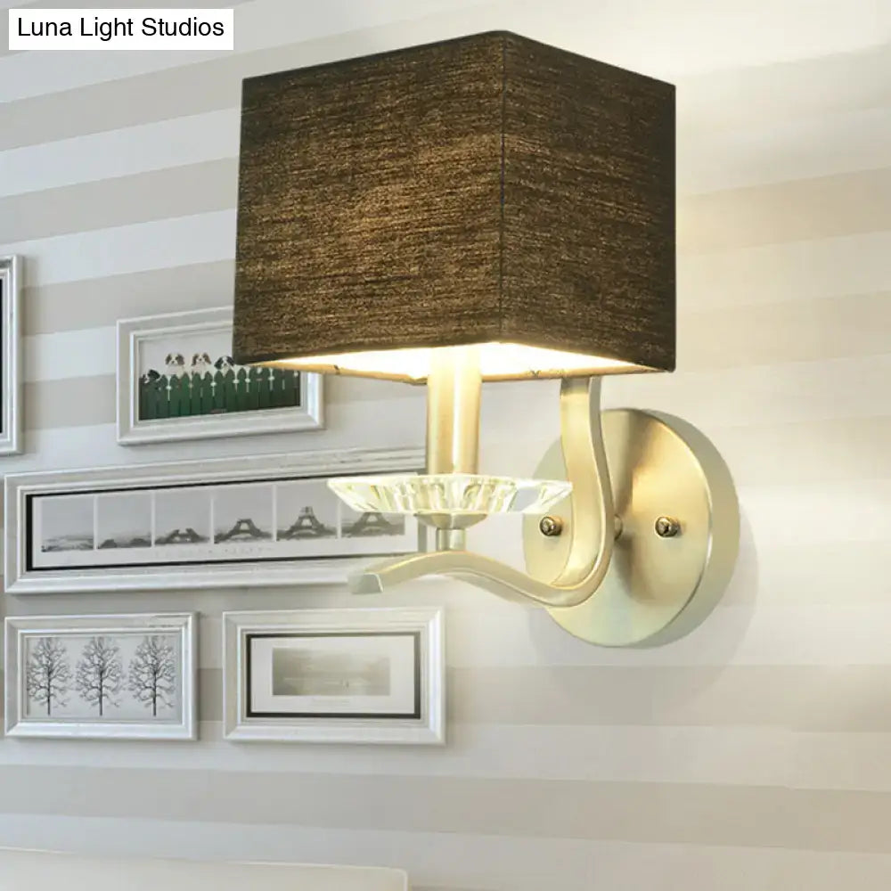 Modern brushed nickel bedside wall lamp with cube bedside wall design features a brown fabric shade and brass arm with crystal accent