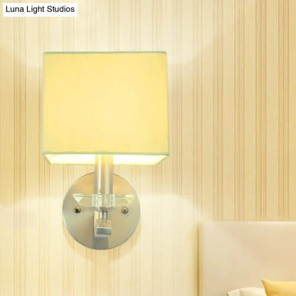 Modern brushed nickel cube bedside wall lamp with pale yellow fabric shade and clear acrylic accents for bedroom use