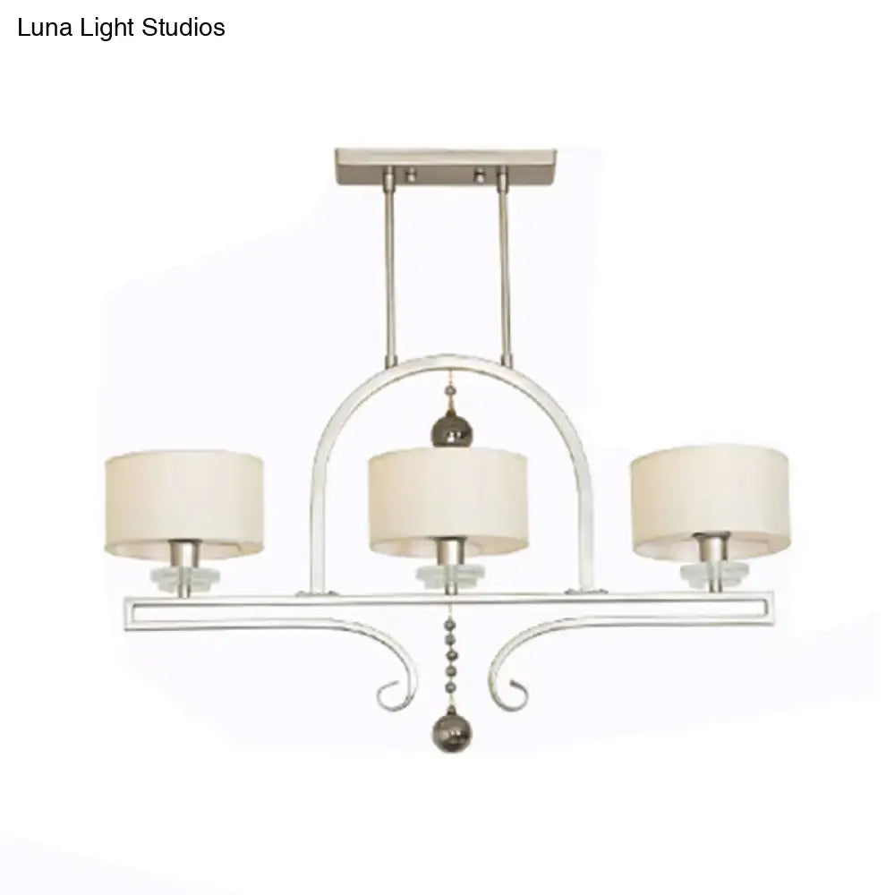 Modern brushed nickel island pendant light with silver-toned metal, cream fabric shades, and decorative crystal accents