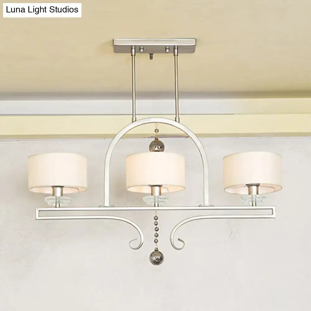 Silver-toned metal island pendant light with three cream fabric shades and crystal glass bead accents for dining room