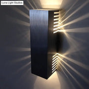 Modern brushed silver wall light with vertical slats emitting warm white light for bedroom sconce lighting