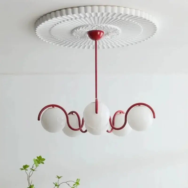 Modern pendant light with burgundy metal arms, white fluted ceiling rose, and three rounded frosted glass shades