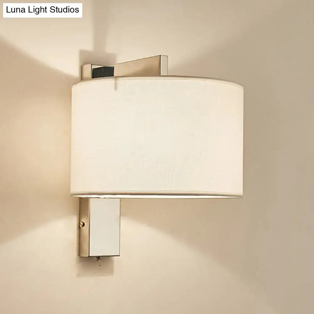 Modern wall sconce with a brushed nickel frame and white fabric drum shade in white black for bedroom lighting