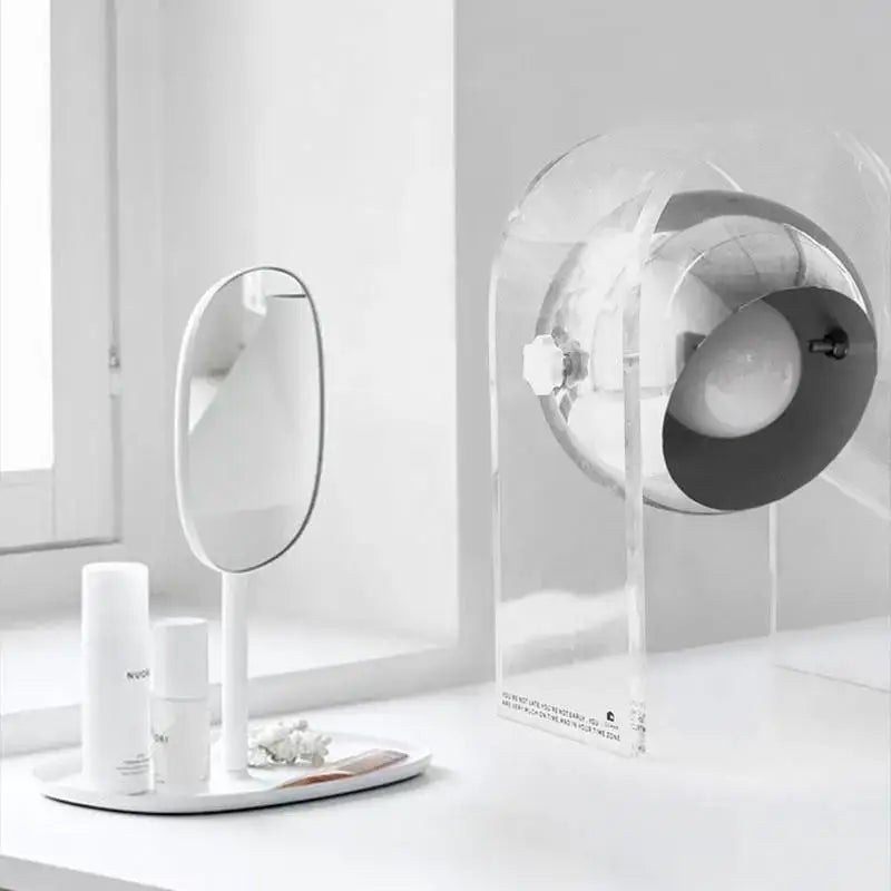 Modern chrome acrylic led desk lamp beside a minimalist white oval vanity mirror for bedroom decorbites acrylic led setup