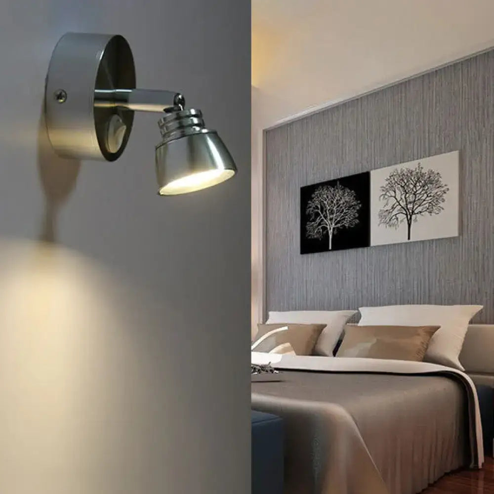 Modern chrome adjustable spotlight wall sconce with silver metal shade and frosted glass providing warm white light