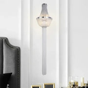 A modern chrome aluminum chain sconce featuring cascading glass prisms for bedroom wall lighting