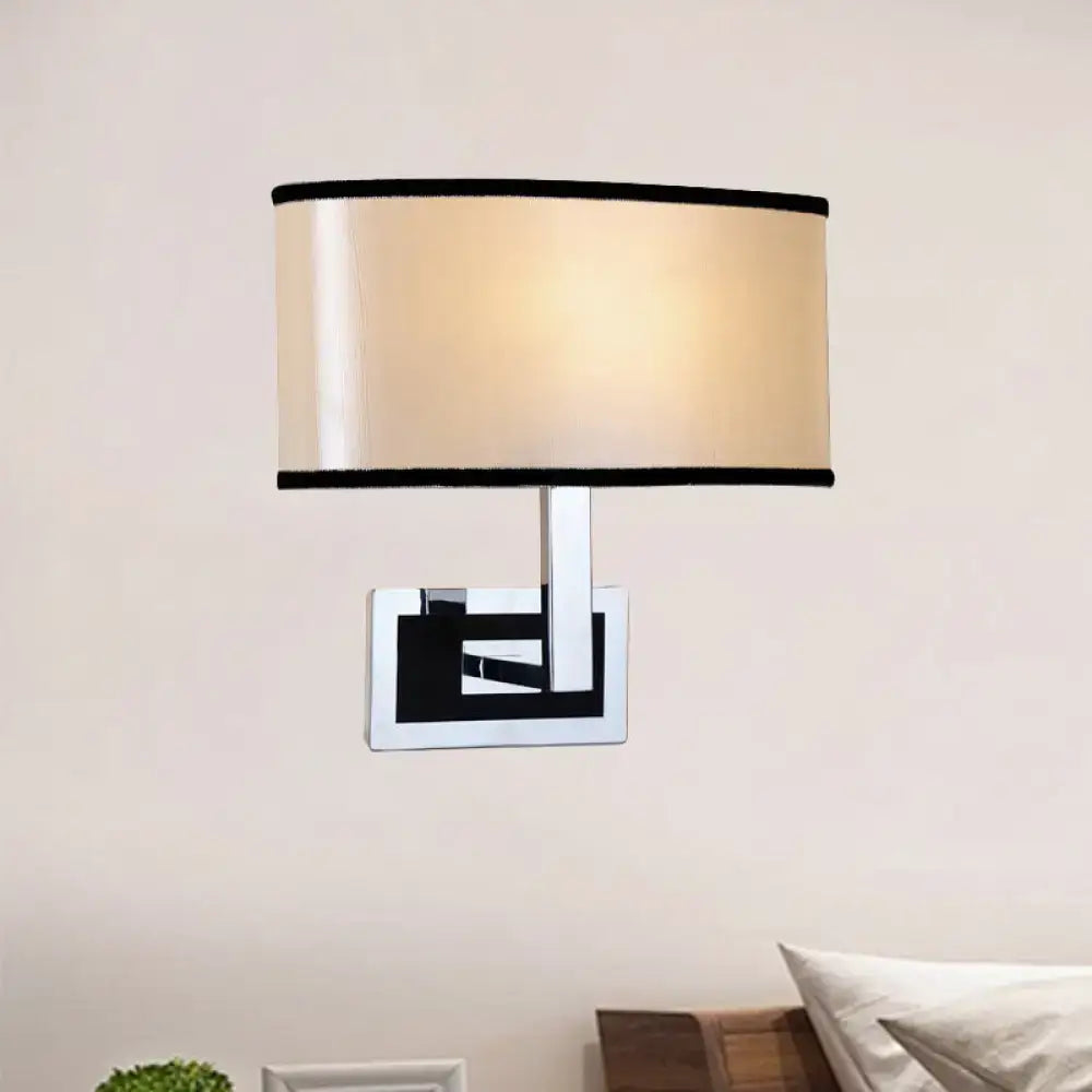 Modern chrome and beige oval wall sconce with a sleek rectangular base and black geometric accents for bedroom lighting