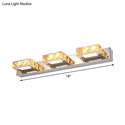 Modern chrome and gold crystal vanity sconce with three illuminated amber crystal accents on sleek stainless steel base