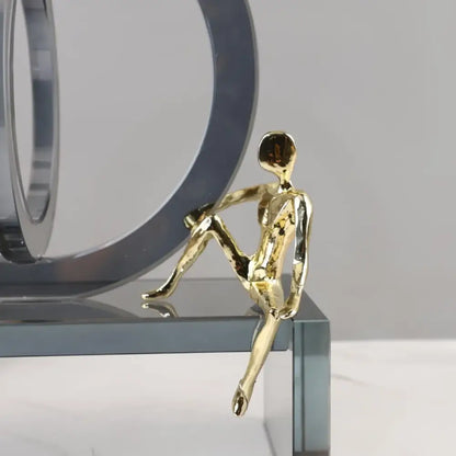 Golden metallic figurine of a seated human form with smooth reflective surfaces for modern geometric crystal rings decor
