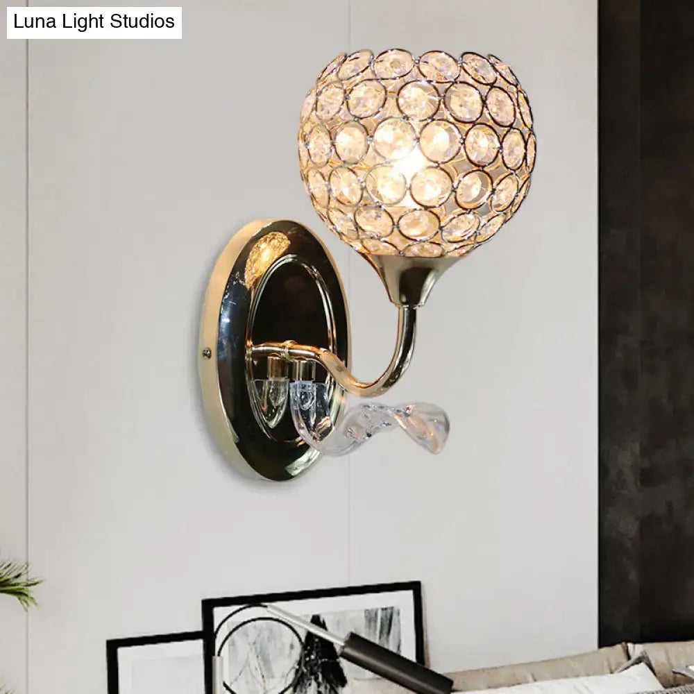 A modern bedroom wall sconce with a polished gold metal base and clear faceted crystal globe in concentric circles