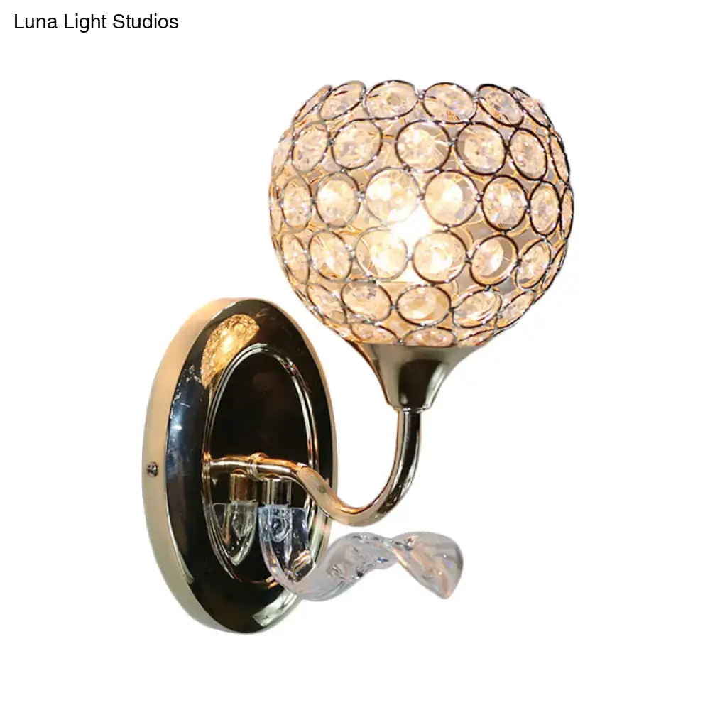 A glamorous crystal globe wall sconce with polished brass finish and clear faceted crystals in concentric circles