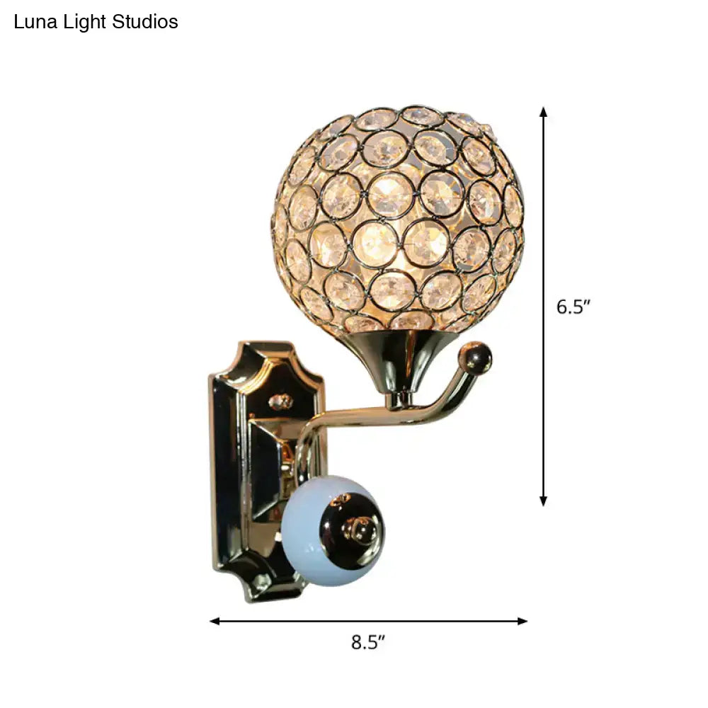 Modern chrome and light blue crystal globe sconce with spherical crystal globe and ornate gold metal base for bedroom walls