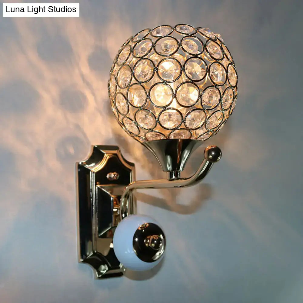 A spherical crystal wall sconce with a gold-toned metal frame and clear faceted crystals in concentric circles
