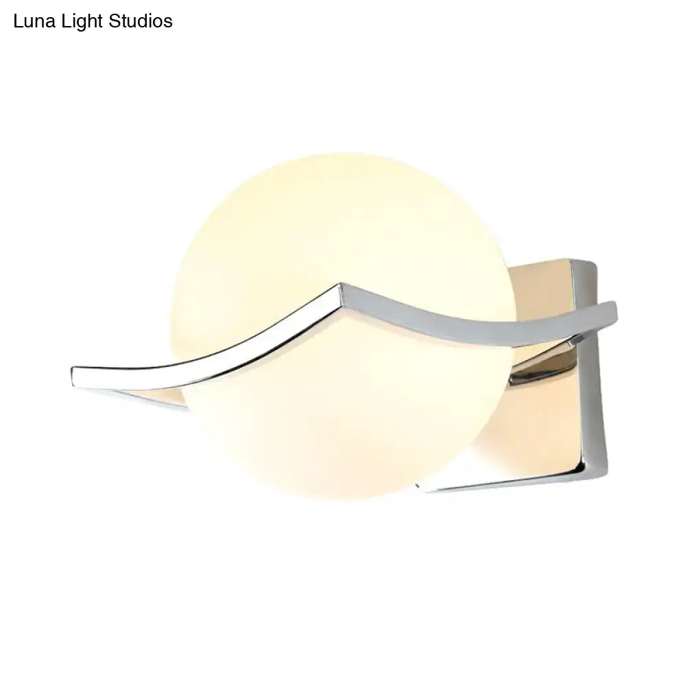 Modern chrome wall sconce with matte white glass globe and sleek curved metal accent for bedroom lighting