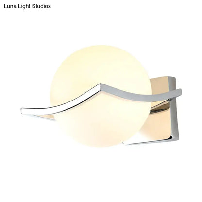 Modern chrome wall sconce with matte white glass globe and sleek curved metal accent for bedroom lighting