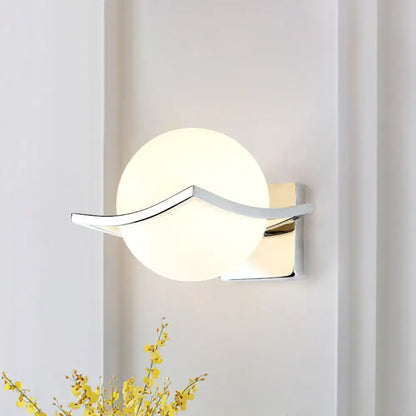 Modern chrome wall sconce with matte white glass globe and sleek curved metal accent for bedroom lighting