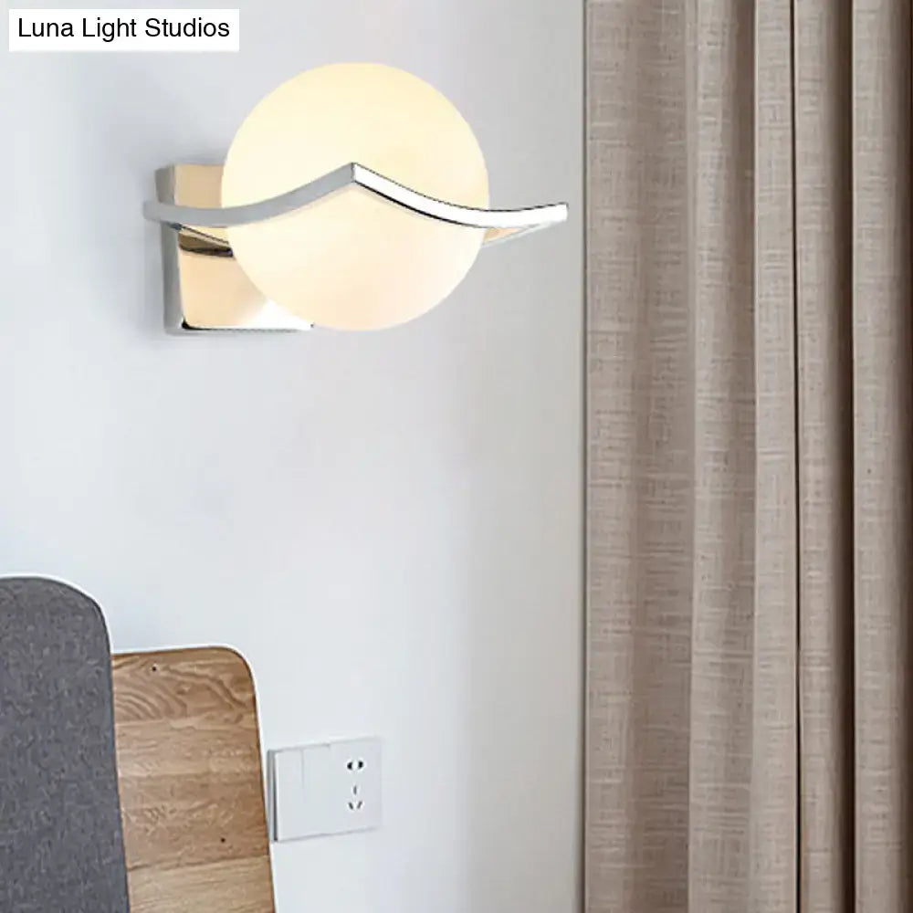 Modern chrome wall sconce with a matte white glass globe and sleek arm for bedroom lighting