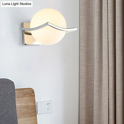 Modern chrome wall sconce with a matte white glass globe and sleek arm for bedroom lighting