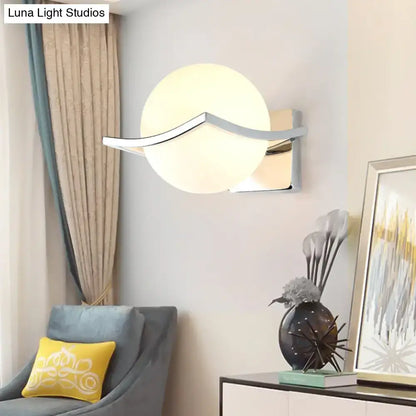Modern chrome wall sconce with matte white glass globe and elegant curved arm for bedroom lighting