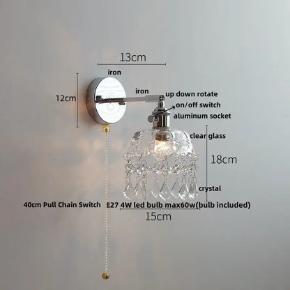 Modern chrome wall light fixture with polished iron arm, clear glass shade, and faceted crystal droplets for bedroom use