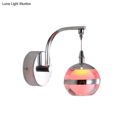 Modern chrome and pink glass wall sconce light with spherical globe and warm internal lighting for bedroom decor