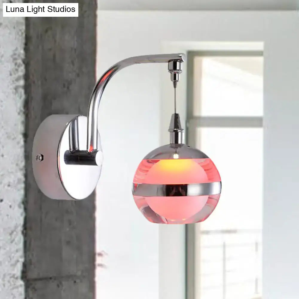 Modern chrome and pink glass wall sconce light with a polished finish and glowing spherical globe for bedroom decor
