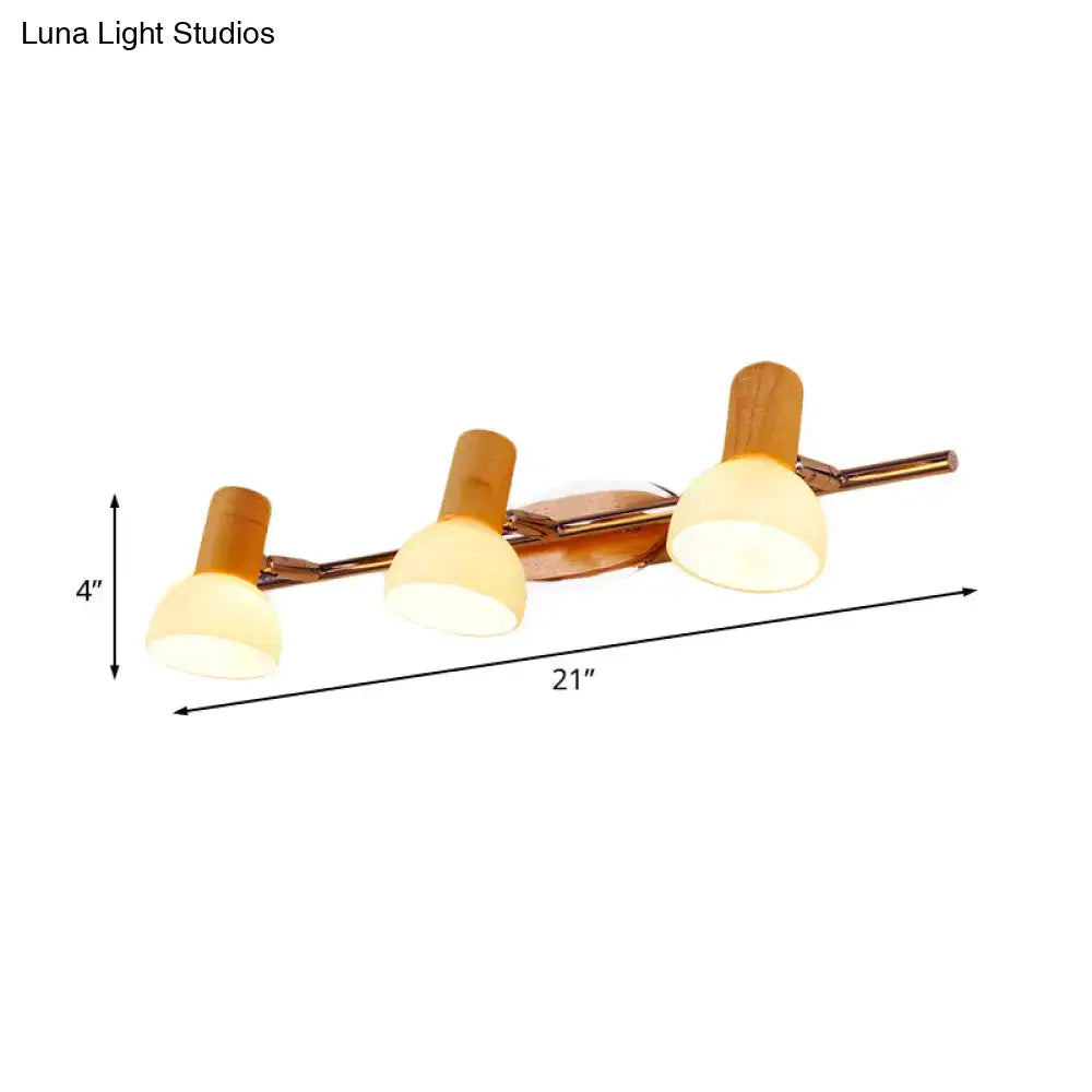 Modern three-light vanity fixture with warm brass finish, bamboo accents, and white glass dome for bathroom use