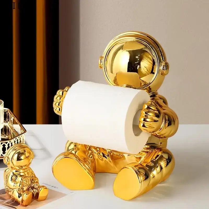 Modern chrome astronaut tissue box holder in metallic gold finish holding white tissue roll for living room use