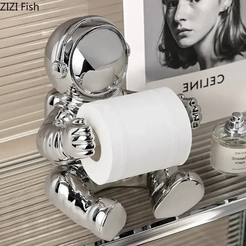 Shiny chrome astronaut tissue box figurine holding a roll of toilet paper for modern living room decor