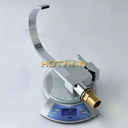 Modern chrome and brass dual hole kitchen tap with curved spout and brass threaded connection on a digital scale
