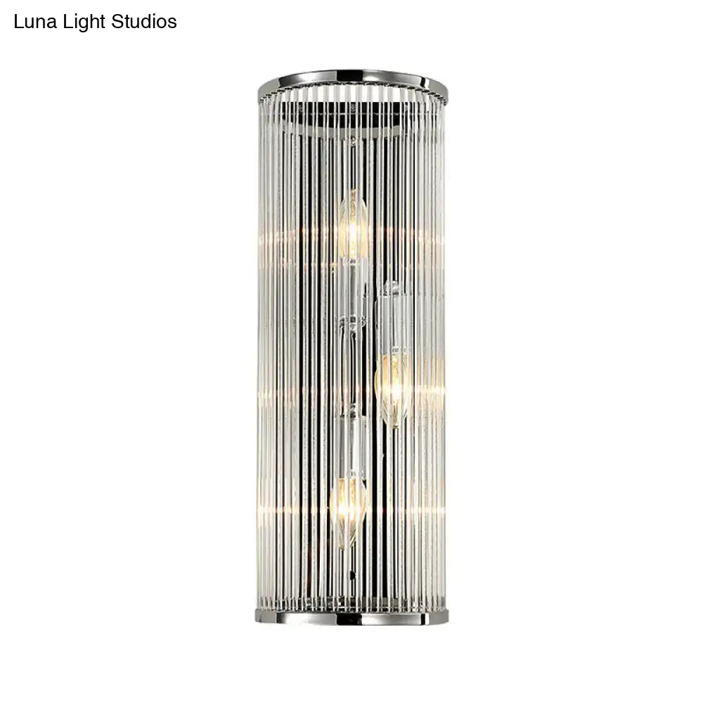 Modern chrome cylindrical wall light with clear crystal shade featuring vertical glass rods and three exposed filament bulbs