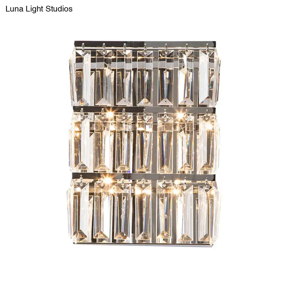 A sleek modern chrome wall lamp with three tiers of clear crystal prisms for bedroom rectangle sconce lighting