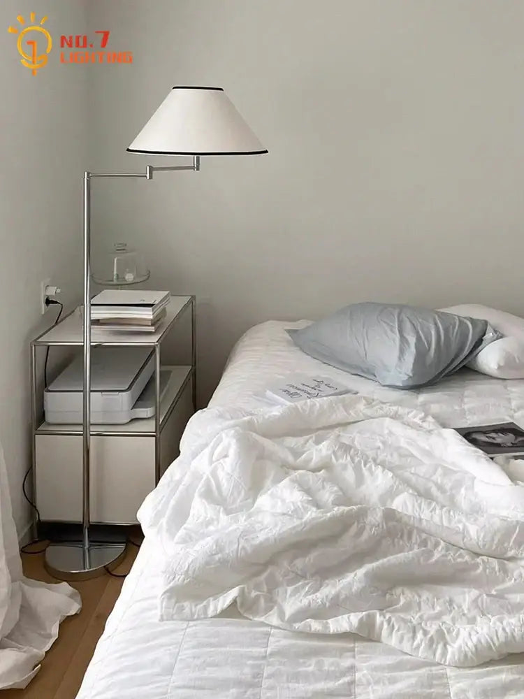 A sleek modern chrome cream rocker arm floor lamp with white conical shade and black trim for living room use