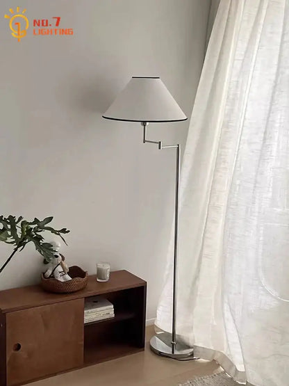 A sleek silver chrome floor lamp with cream rocker arm and white conical shade with black trim for living room