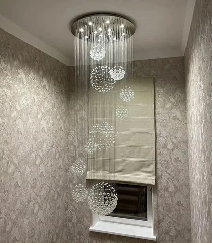 A modern chrome crystal ball design chandelier set with circular metallic base and cascading clear glass orbs for staircases