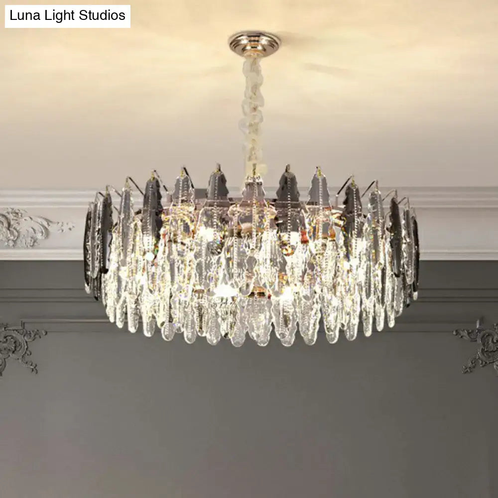 A modern drum pendant light with clear k9 crystal teardrop prisms and dark metallic accents on a twisted chrome chain