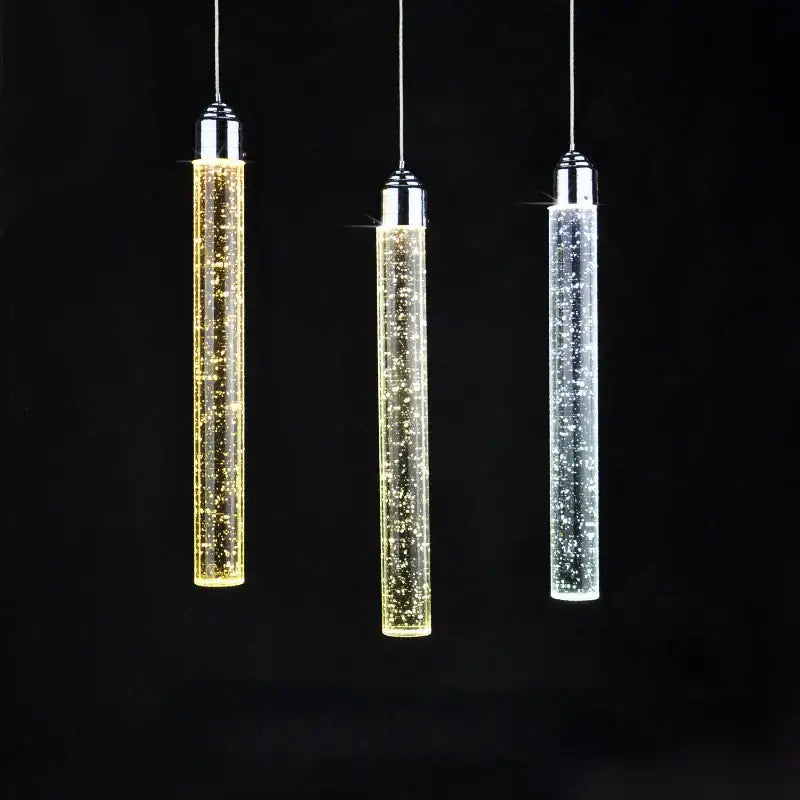 Three modern crystal led pendant lights with chrome tops and glass bodies glowing in gold warm white and cool white hues