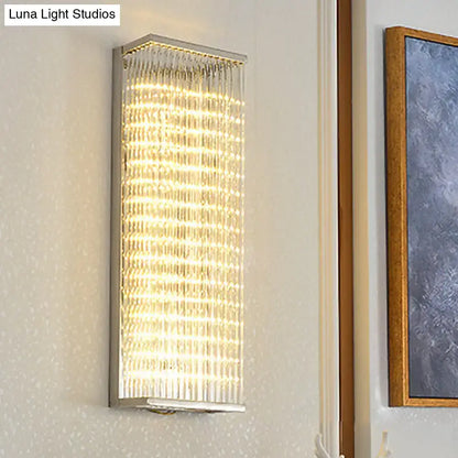 A modern chrome led wall sconce featuring vertical crystal rods within a polished metallic frame for living room or bar lighting
