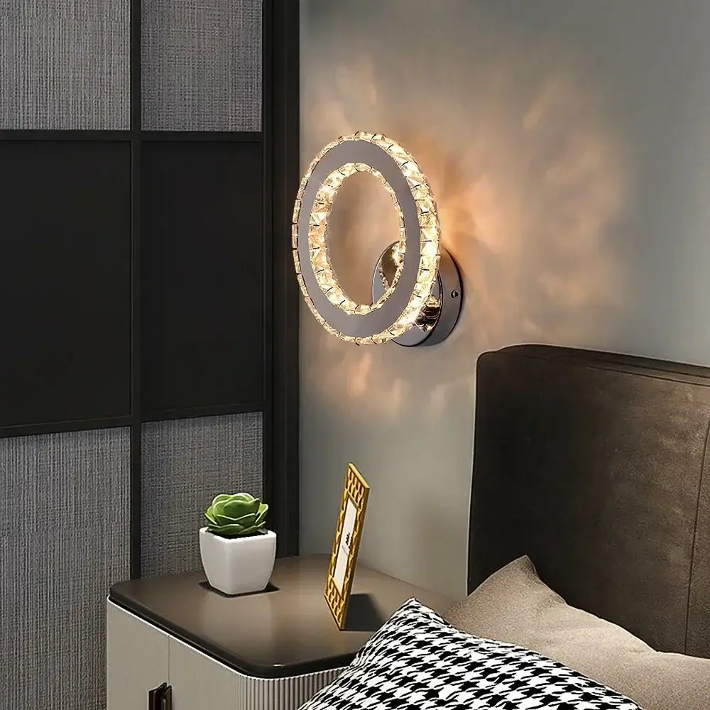 A modern chrome crystal led wall sconce with faceted crystal ring emitting warm ambient light for living room decorbites crystal led