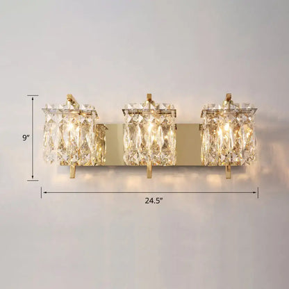 Gold-toned modern wall mount sconce light with three crystal shade fixtures for bedroom illumination