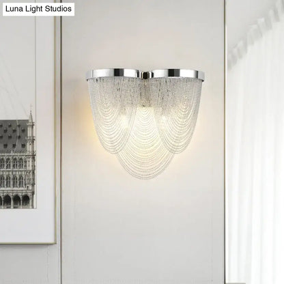 A modern chrome crystal tassel wall lamp with cascading clear beads for elegant living room lighting