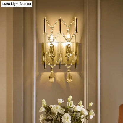 Gold-toned crystal wall sconce light type with dangling teardrop crystals for modern bedroom lighting