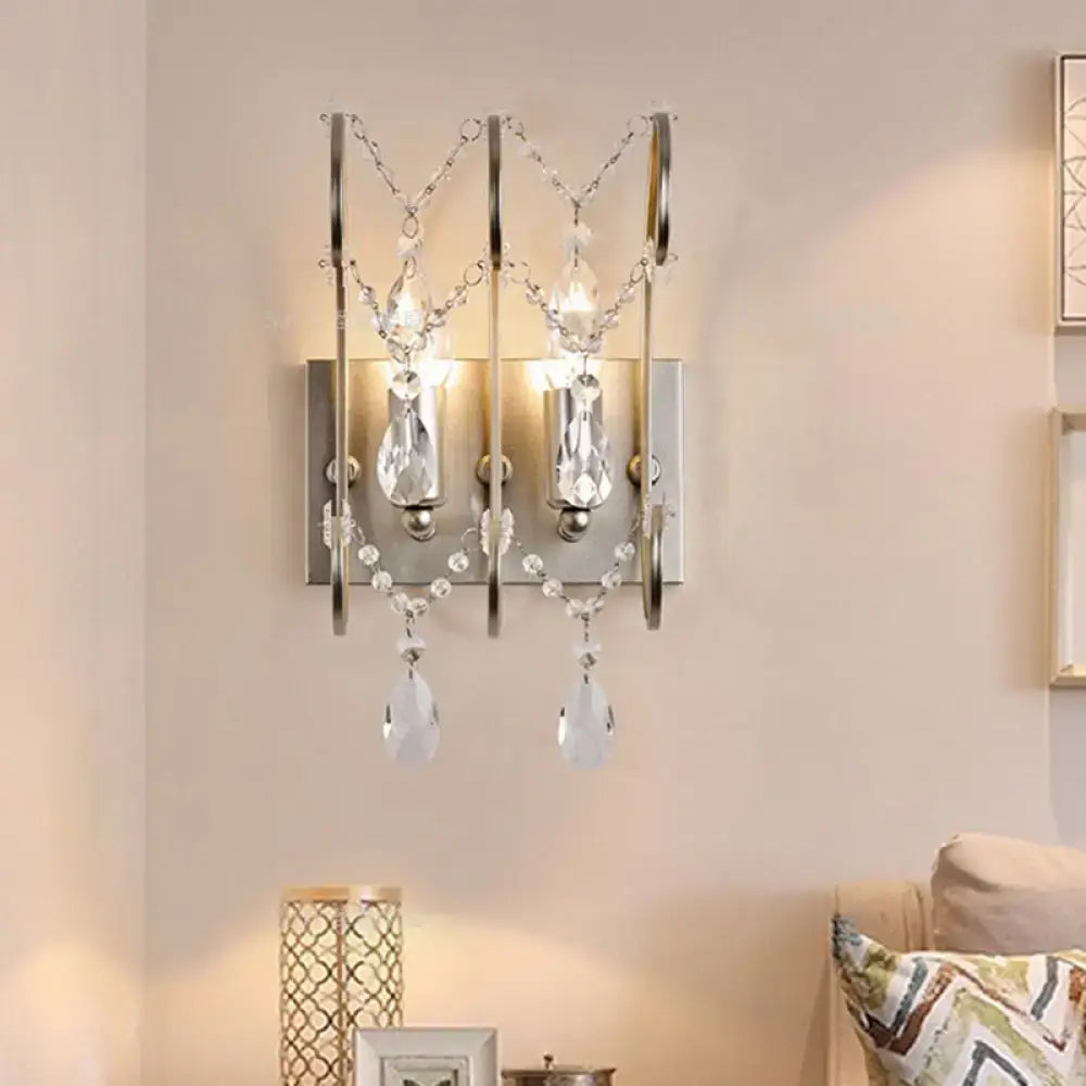 A modern chrome crystal wall sconce light type with polished chrome frame and dangling crystal teardrops for bedroom
